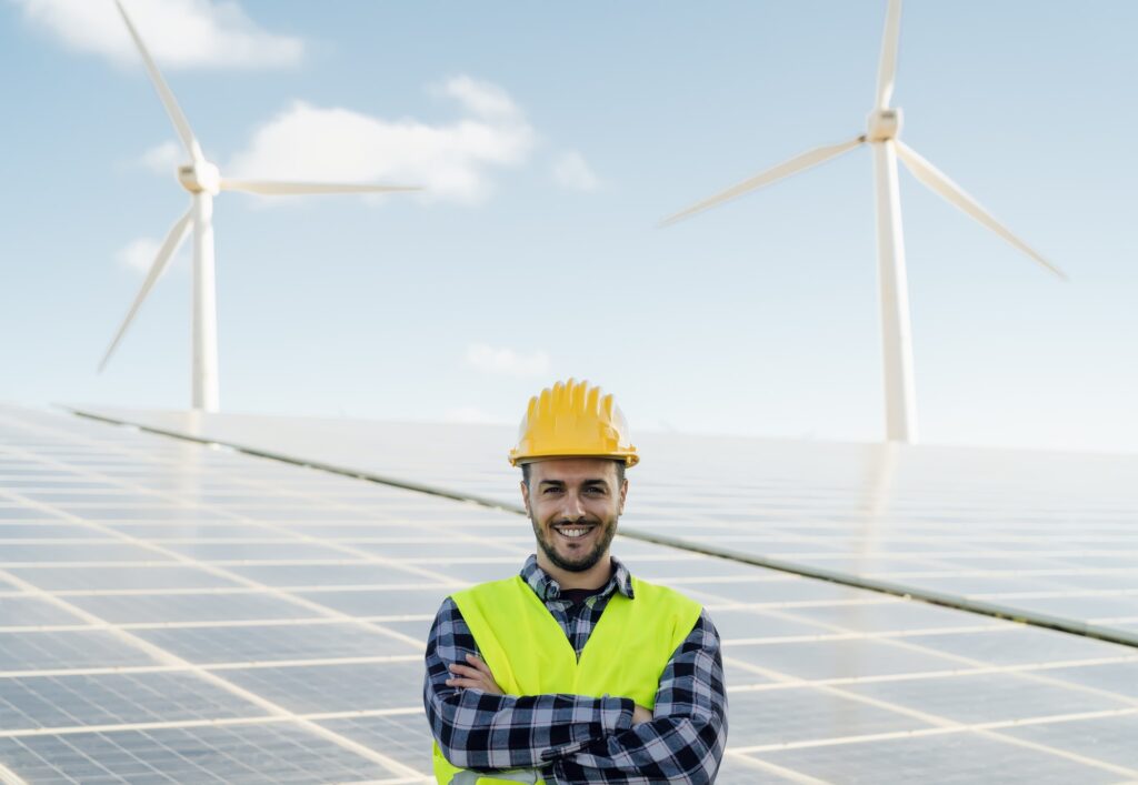 Young male engineer working for alternative energy with wind turbine and photovoltaic panels
